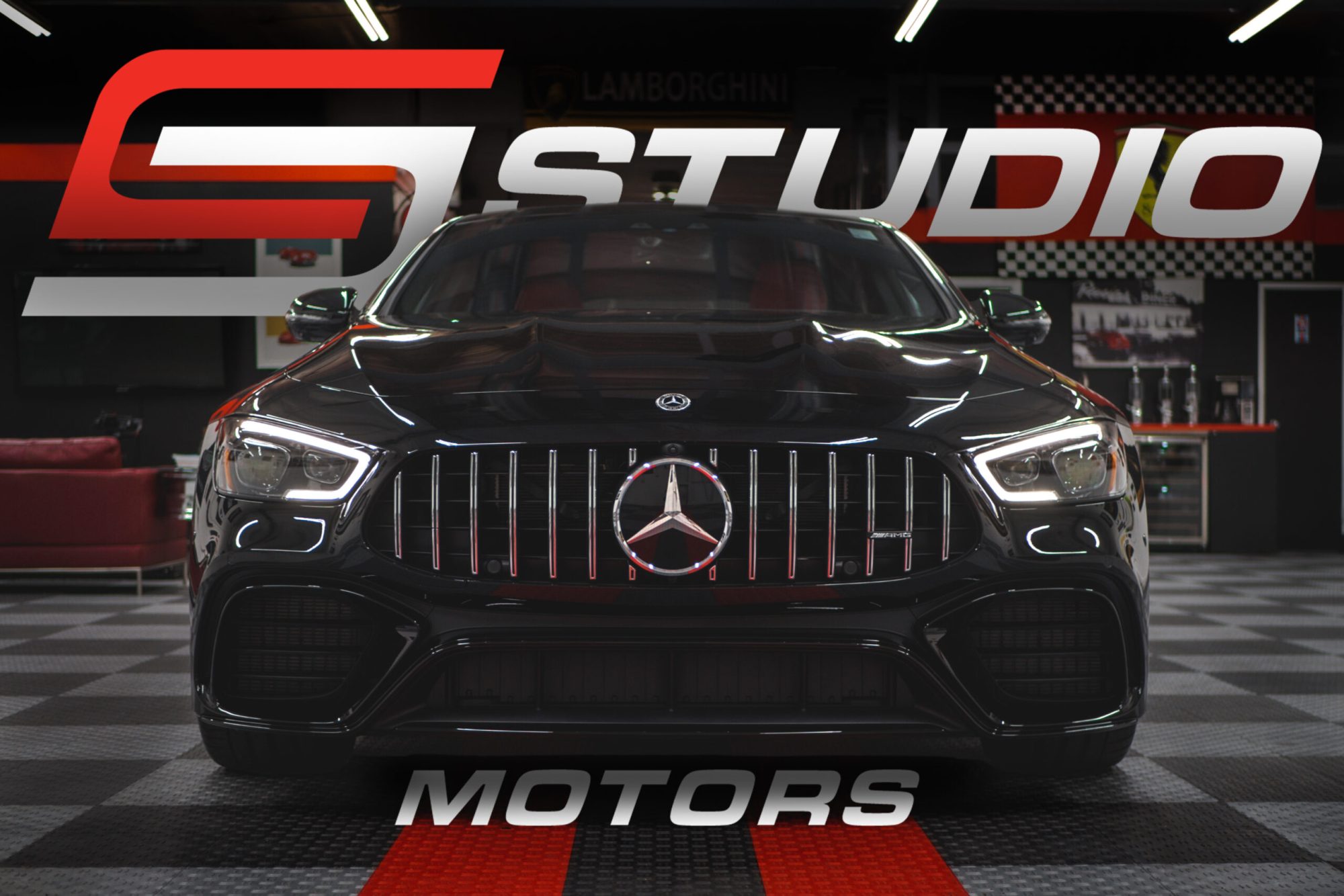 The Studio Motors wordmark set over a black Mercedes-AMG GT 4-door on the showroom floor